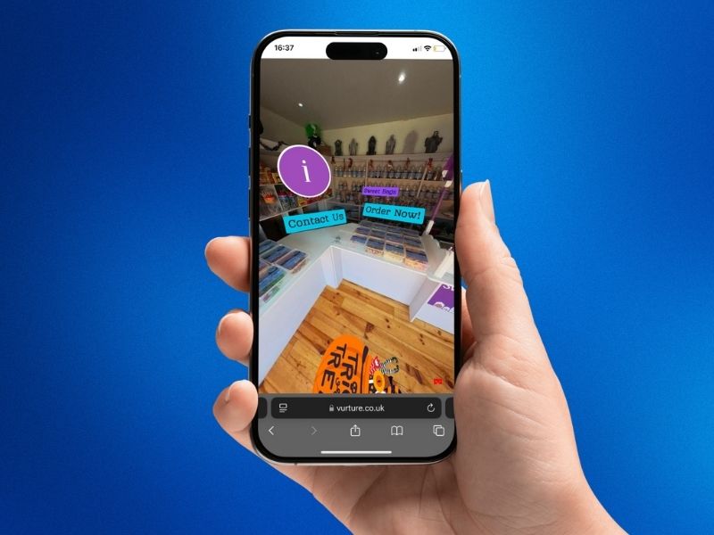 Mobile phone showing a 360° virtual tour of a business with interactive buttons, viewed in a realistic hand-held mockup.
